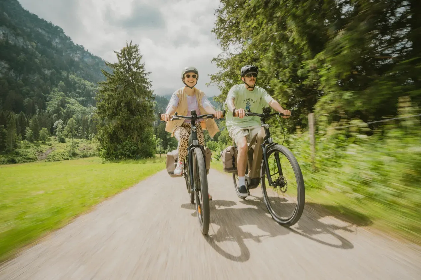 Deux cyclistes sur des Decathlon E-ACTV 900 chargés de sacoches, sur un chemin de vallée