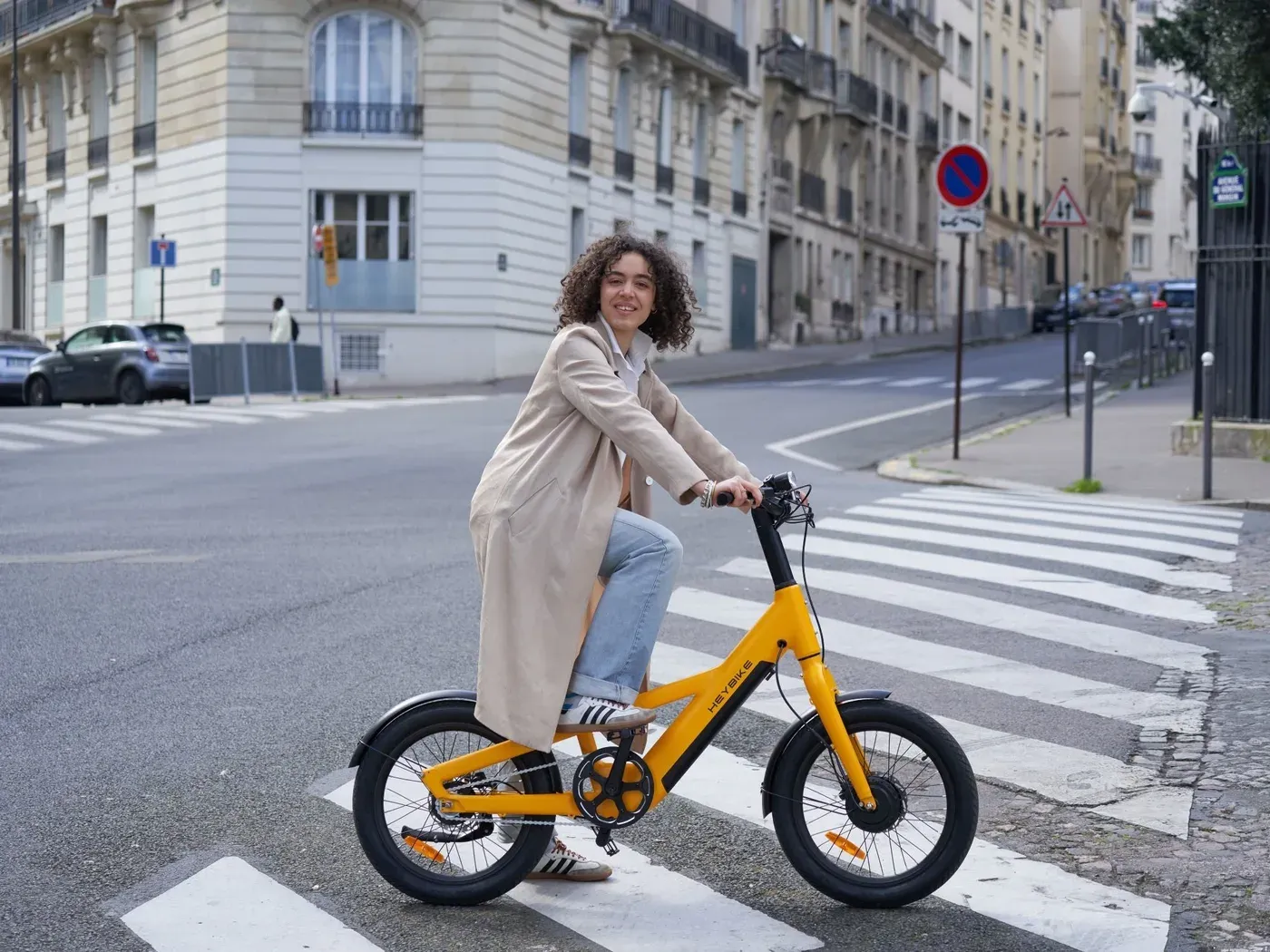 Une cycliste arrêtée sur un passage piéton parisien avec un Heybike EC Compact City jaune